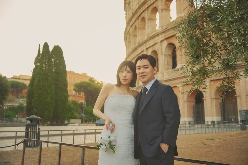 콜로세움을 배경으로 서로 기대어 서 있는 웨딩 커플